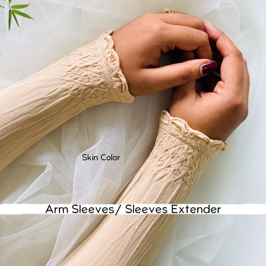A close-up of a person's hands and forearms wearing cream-colored textured arm sleeves with ruffled cuffs, styled over sheer white tulle fabric. Text on the image reads 'Skin Color' and 'Arm Sleeves / Sleeves Extender'.