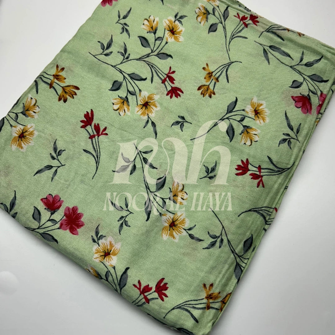 a close up photo of green printed hijab by modal hijab by noor al haya