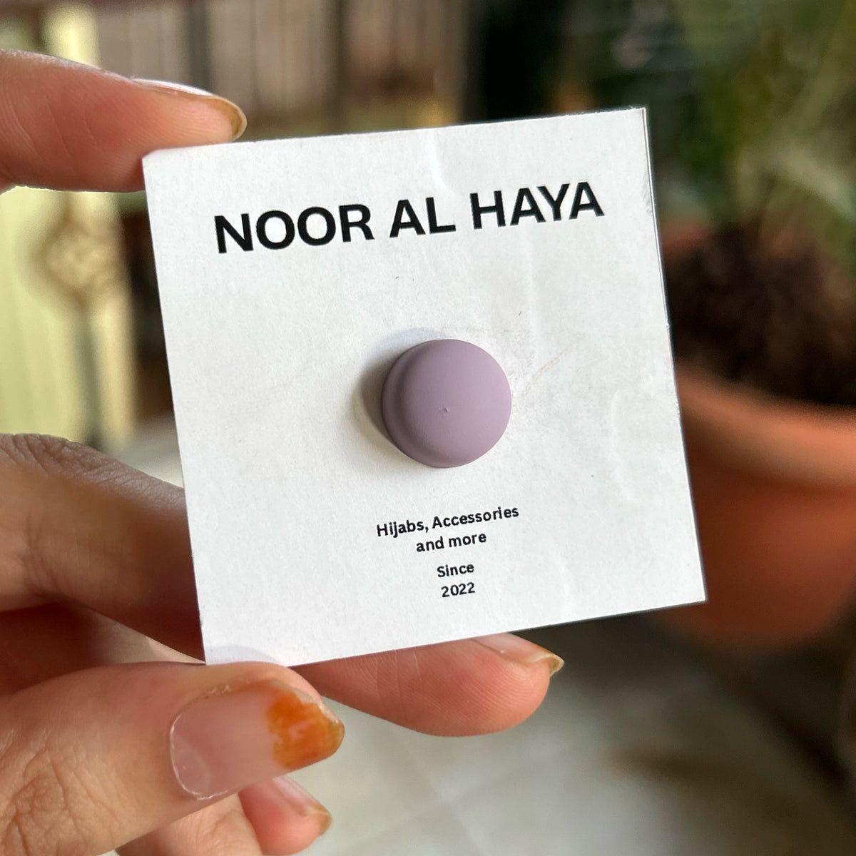 Woman holding a lavender hijab magnet by Noor Al Haya on branded card