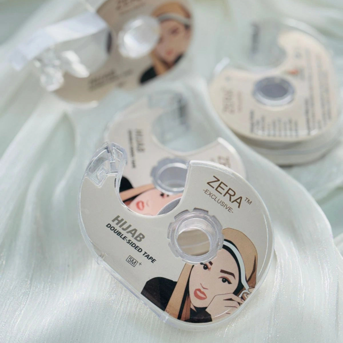 Zera hijab styling tape with packaging on a light fabric background