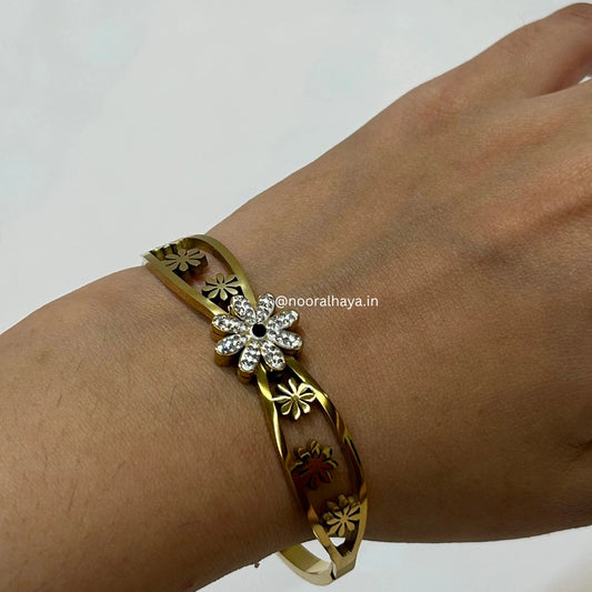 Woman wearing a gold flower bangle by Noor Al Haya