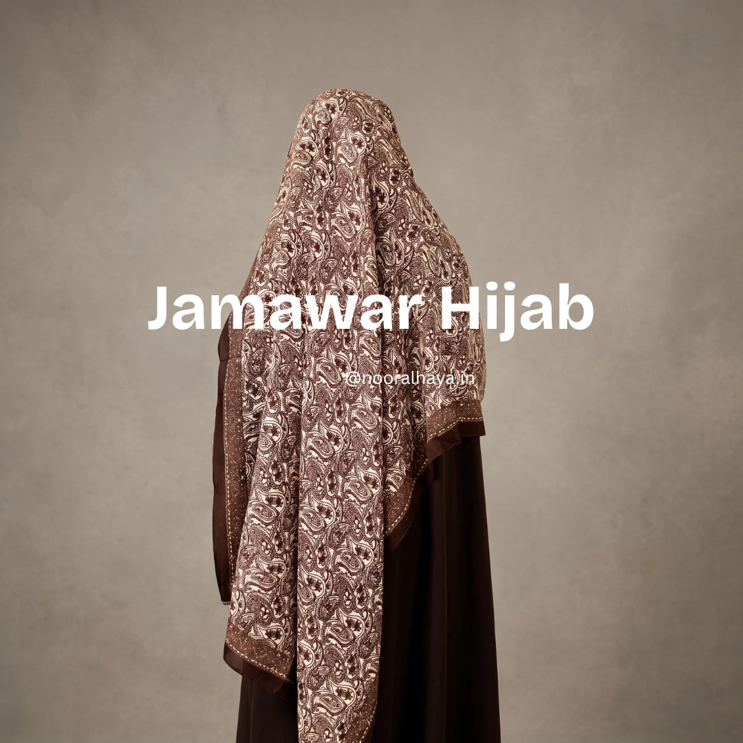 A woman wearing a brown embroidered hijab with floral patterns, shown from the back against a textured gray background. White text overlay reads 'Jamawar Hijab' with a smaller watermark 'jamawar hijab' below it. a model wearing jamawar hijab by noor al haya