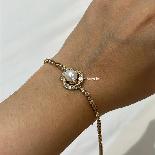 A gold-plated chain bracelet with a central round pearl and a halo of small clear stones, shown worn on a person's wrist against a light neutral background.