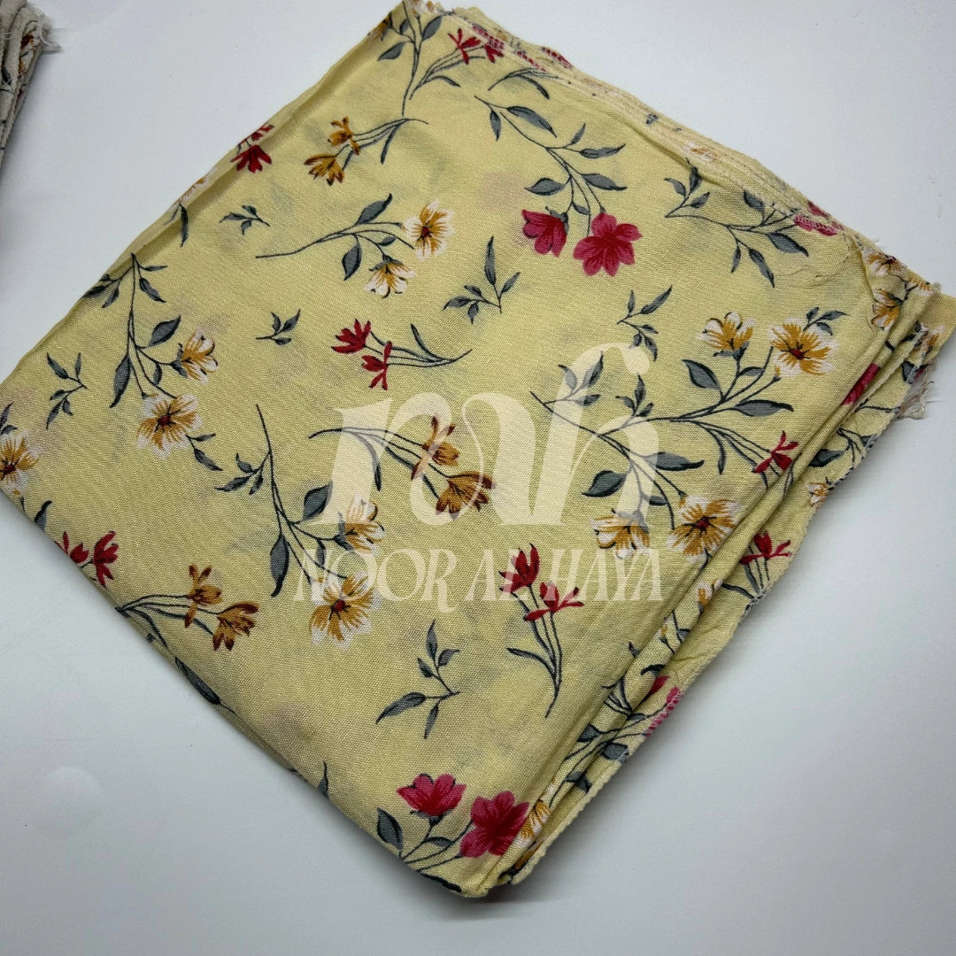a close up photo of yellow floral printed hijab by noor al haya